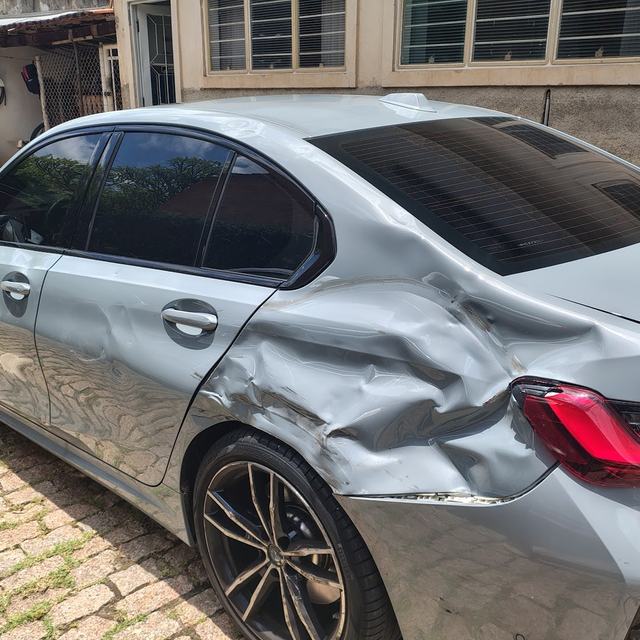 BMW prata com a lateral traseira amassada, antes do reparo